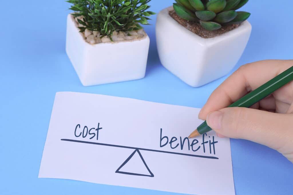 Weighing scale balancing cost against benefit, illustrating how much real estate coaching costs versus the return it produces